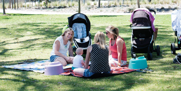 Image of women and children on a picnic blanket in a park