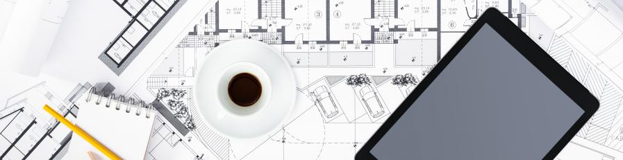 Image of a pair of glasses, cup of coffee and a tablet device sitting on top of building plans