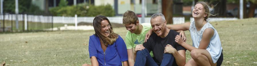 Image of mother, son and father sitting on lawn smiling